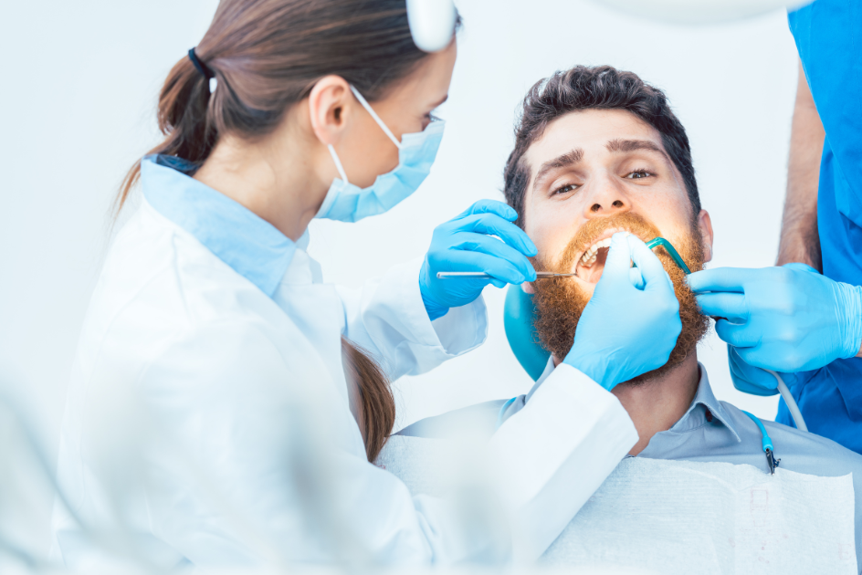 Dentist performing an oral exam on a bearded man